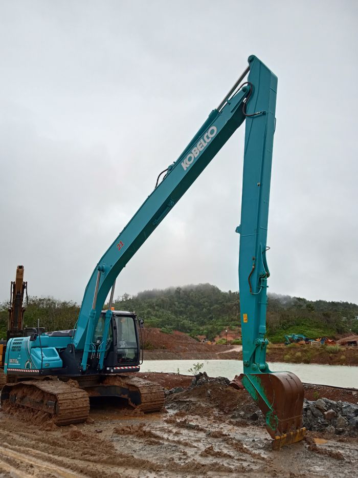 Excavator at work in a muddy site near water in Sukabumi, Indonesia. Earthmoving equipment.