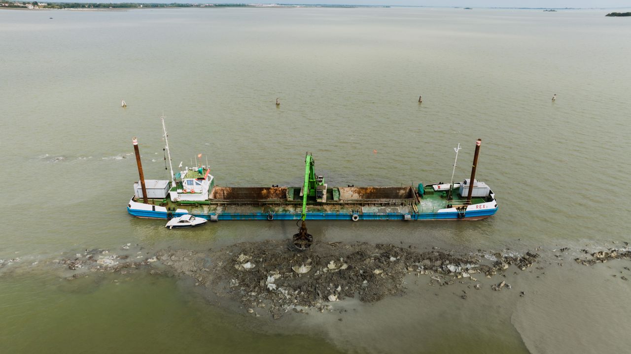 Aerial view of a dredging barge in the Venice lagoon performing excavation work.