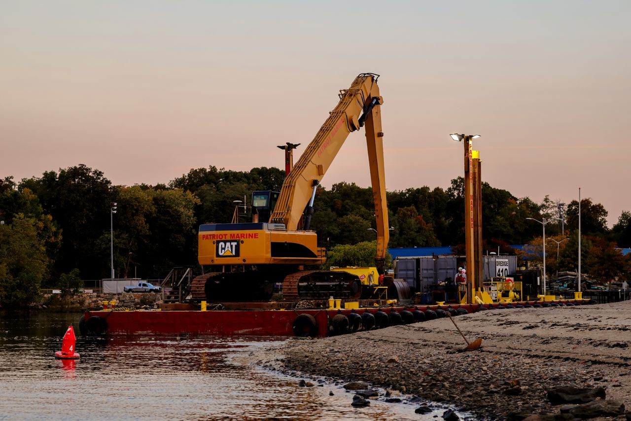 An excavator on a barge near Cove Island Park Marina during twilight in Stamford, Connecticut.